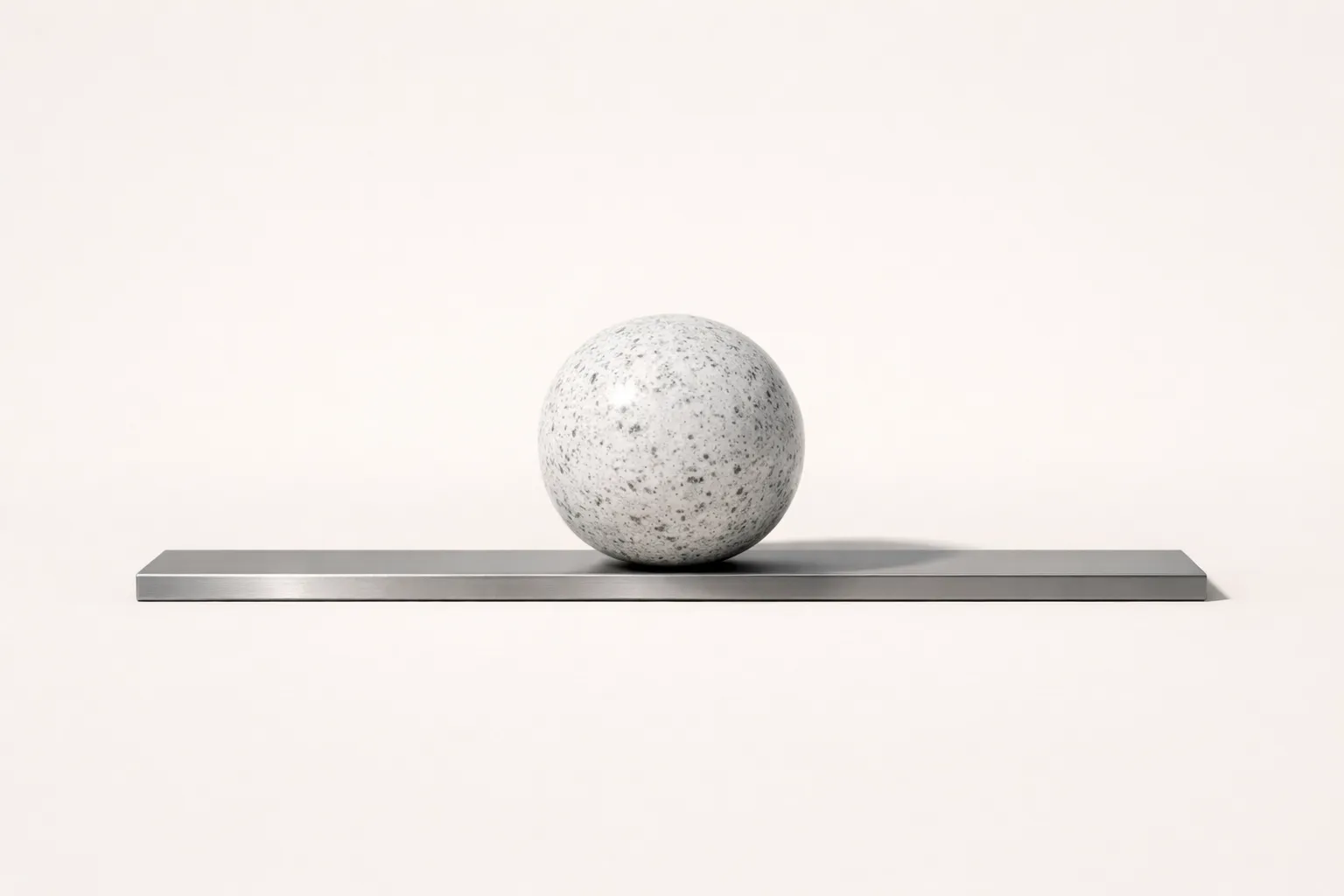 A granite sphere on a titanium slab illustrating structural coherence and independent internal authority.